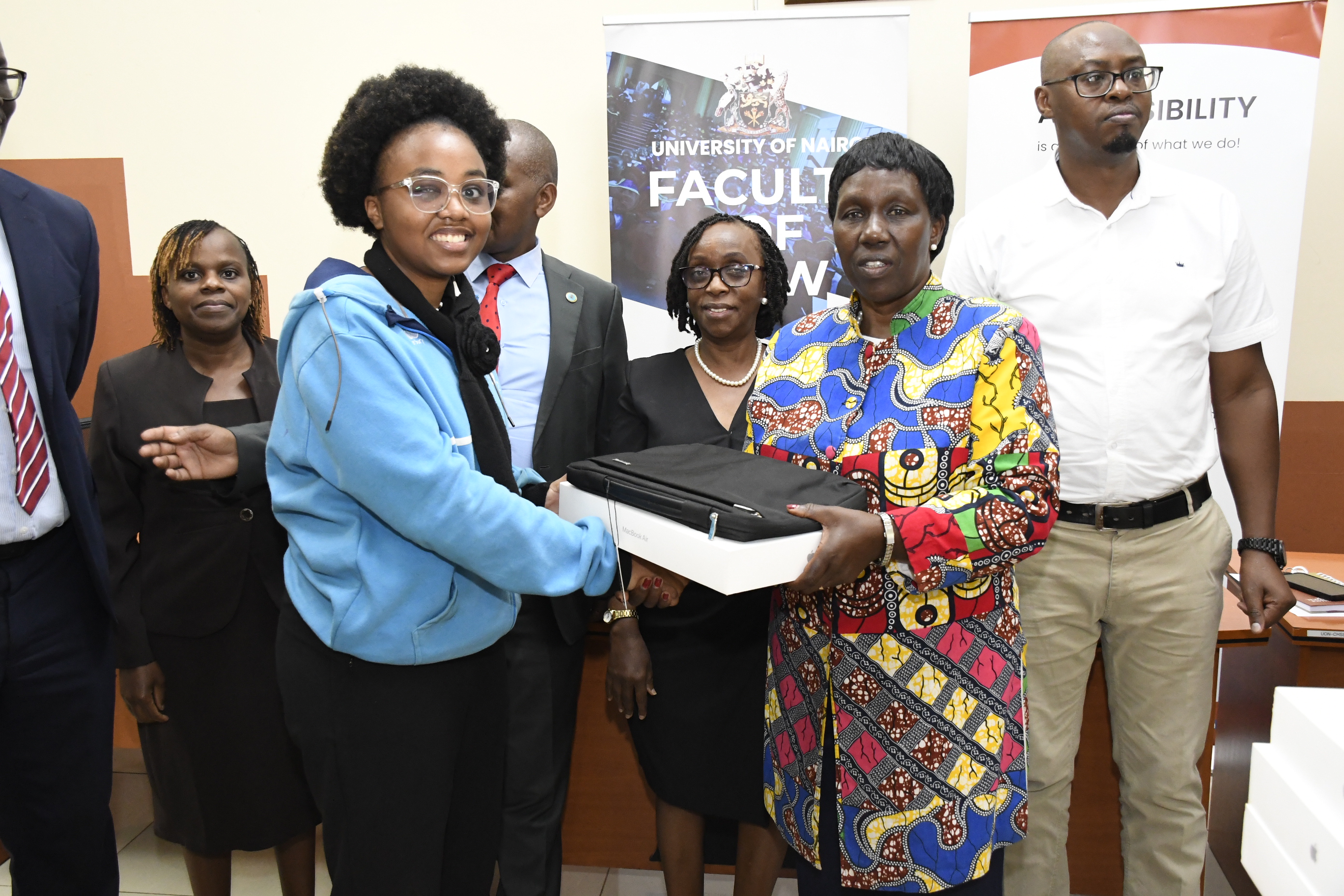 The VC presenting a MacBook to one of the beneficiaries