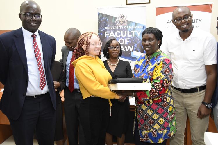 The Vice Chancellor (Ag) Prof Margaret Hutchinson hands over a MacBook to one of the beneficiaries of the initiative.