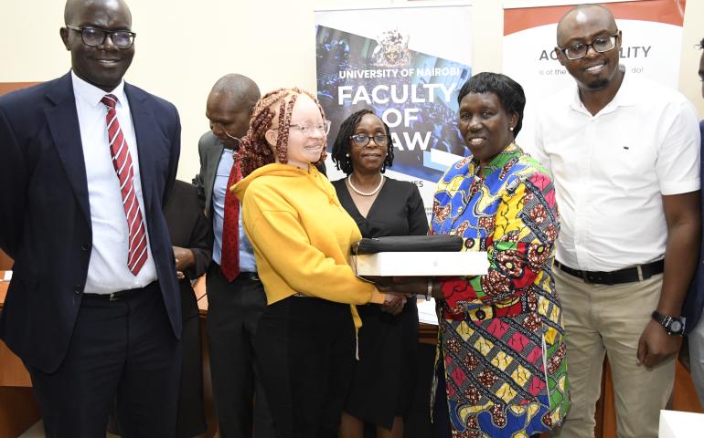 The Vice Chancellor (Ag) Prof Margaret Hutchinson hands over a MacBook to one of the beneficiaries of the initiative.